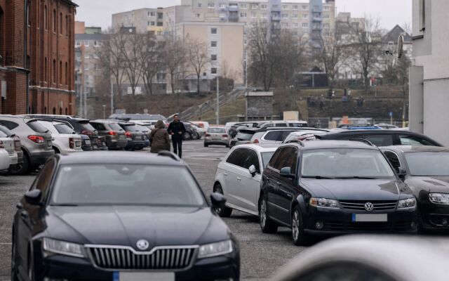 Preplnené parkovisko v Bratislave s autami a mestskou architektúrou v pozadí