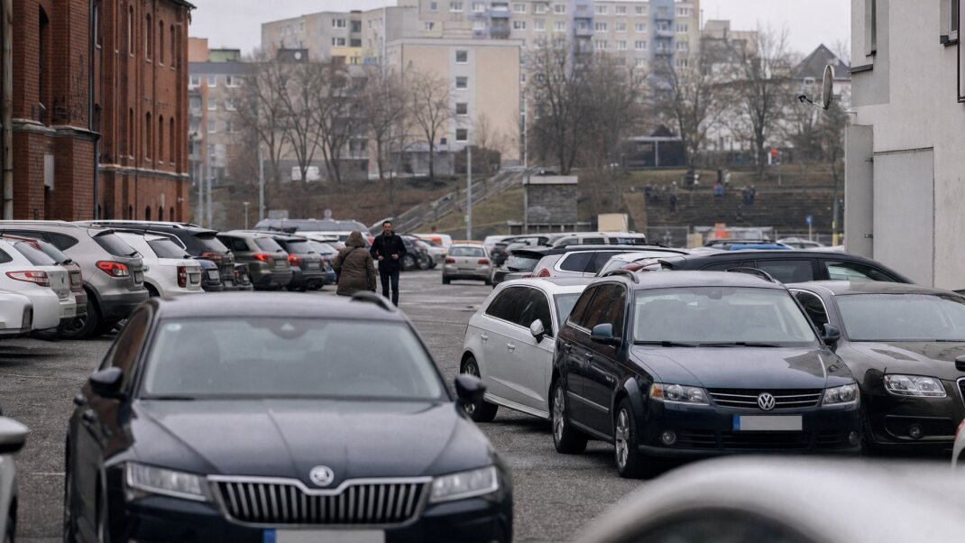 Preplnené parkovisko v Bratislave s autami a mestskou architektúrou v pozadí