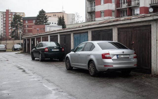 Vonkajšie parkovisko s autami v slovenskom meste, porovnanie s garážou