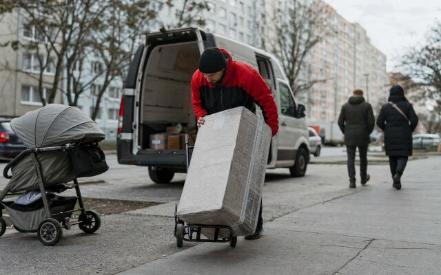 Kuriér s bicyklom na chodníku v Bratislave, obchádzajúci prekážky pri dodávke