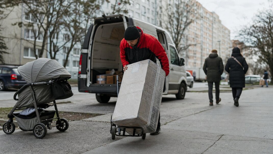 Kuriér s bicyklom na chodníku v Bratislave, obchádzajúci prekážky pri dodávke