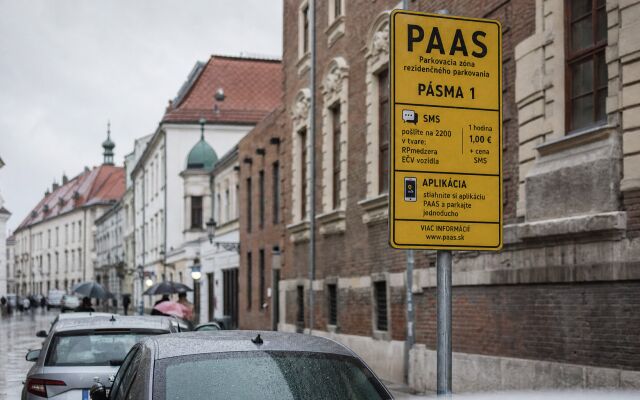Parkovisko v centre Bratislavy s autami a obchodnými centrami v pozadí