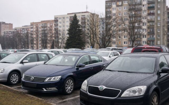 Preplnené parkovisko v Bratislave s automobilmi a mestskou architektúrou