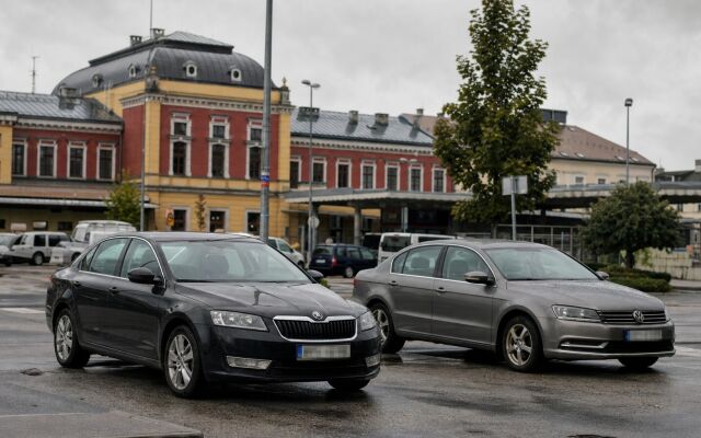 Parkovacie miesta pri železničnej stanici v Žiline s autami a čakajúcimi cestujúcimi