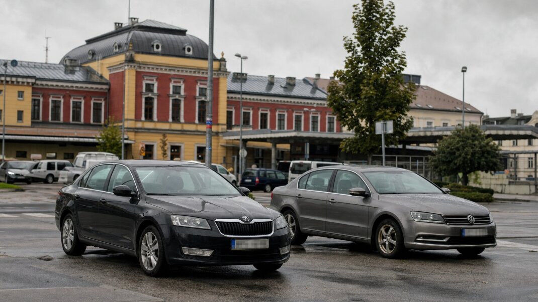 Parkovacie miesta pri železničnej stanici v Žiline s autami a čakajúcimi cestujúcimi