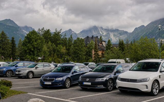 Parkovisko na Štrbskom Plese s výhľadom na Tatry a zaparkovanými autami