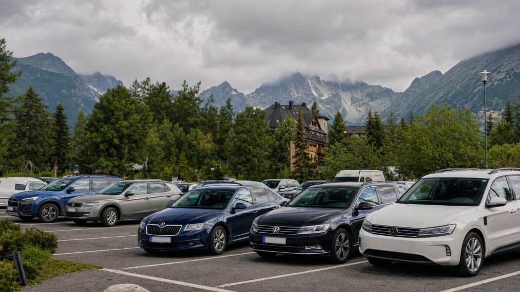 Parkovisko na Štrbskom Plese s výhľadom na Tatry a zaparkovanými autami