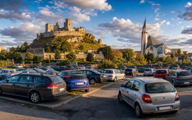 Ilustračný pohľad na Levický hrad a panorámu Levíc s nepravidelne zaparkovanými autami v popredí.