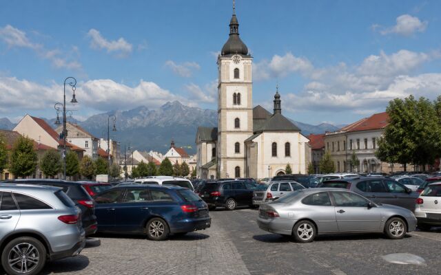 Ilustračný pohľad na Kostol svätého Egídia, centrum Popradu a Vysoké Tatry s autami zaparkovanými nadivoko v popredí.