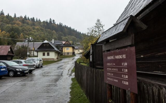 Parkovisko pri vstupe do dediny Vlkolínec s autami a turistami na prechádzke