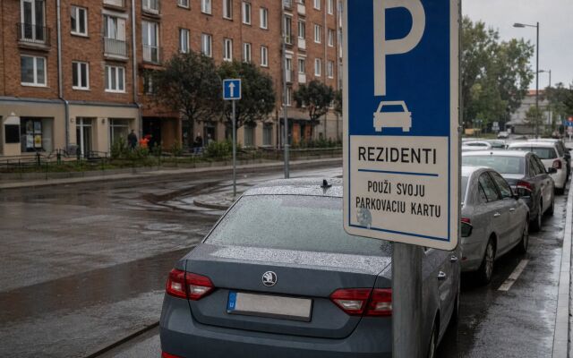 Parkovisko v Trenčíne s autami a mestskou budovou v pozadí
