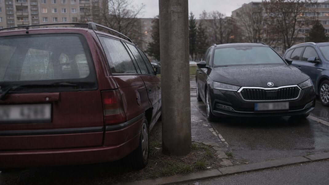 Preplnené parkovisko na sídlisku s autami zaparkovanými tesne pri sebe