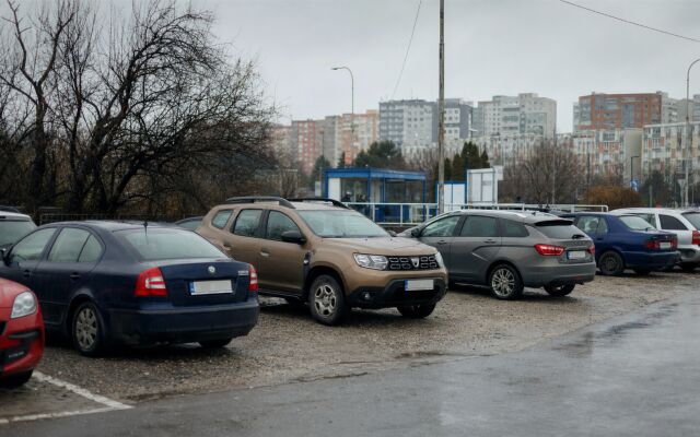 Záchytné parkovisko na okraji mesta s autom a verejnou dopravou v pozadí