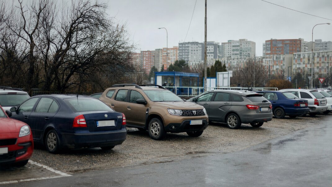 Záchytné parkovisko na okraji mesta s autom a verejnou dopravou v pozadí